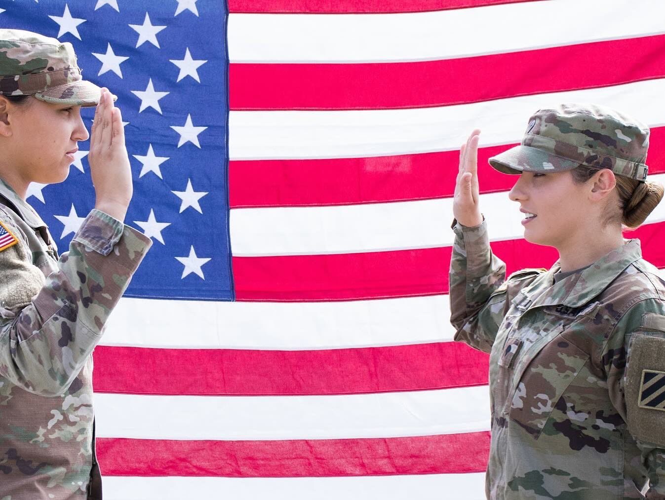 Two soldiers raising their right hands in front of an American flag